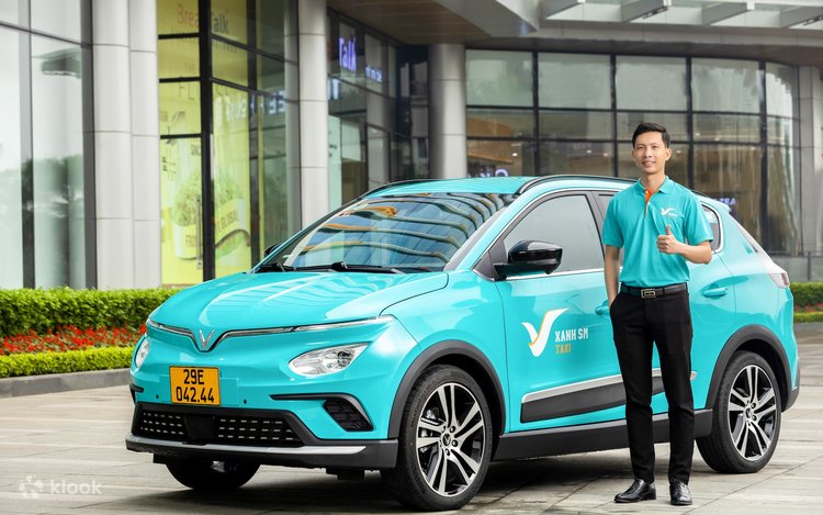 Tài xế đứng cạnh xe taxi điện đón khách